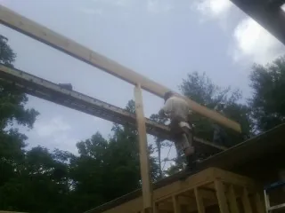Carpenter setting a ridge beam over a new addition frame — Ice Dam Removal by Roofing Brothers in Nichols