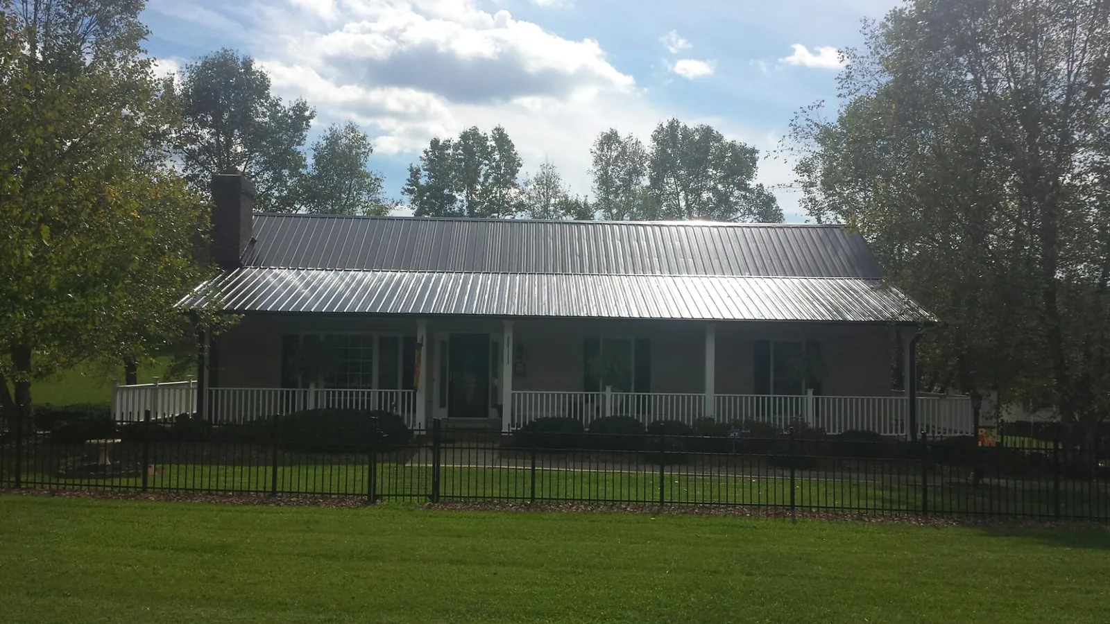 Gray metal roof on a brick ranch with a full width front porch — Gutter Guard Installation work by our crew in Nichols