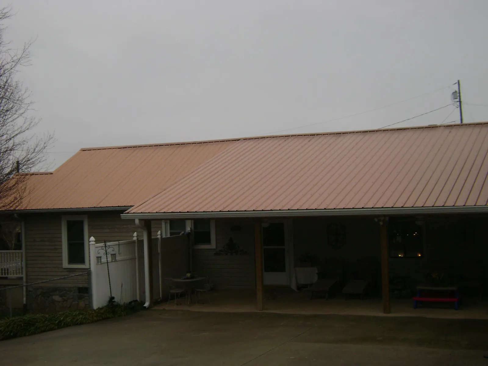 Copper toned metal roof over a wide covered patio in Nichols