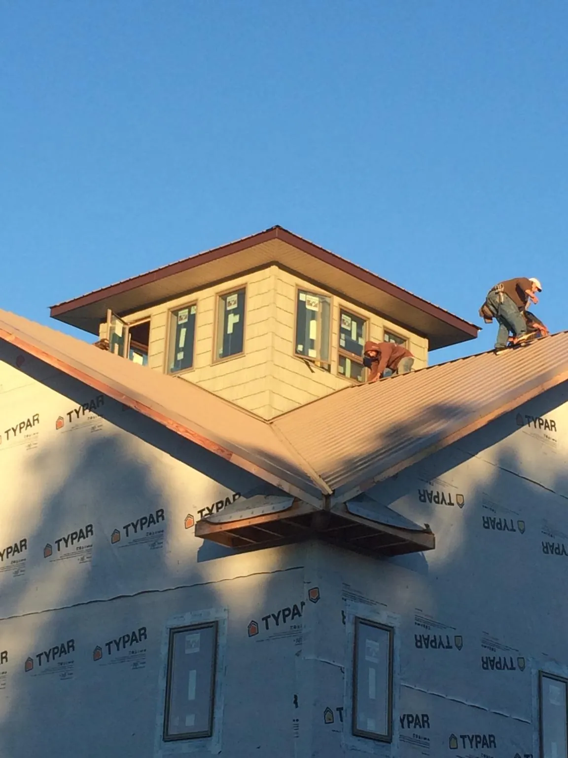 Roofers working around a rooftop cupola on a new metal roof at sunset — Roof Waterproofing in Nichols by Roofing Brothers